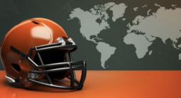 American football helmet on an orange surface with a world map in the background, symbolizing the international expansion of the NFL.