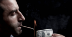 man smokes cigar while burning money