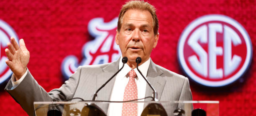 Nick Saban standing in front of SEC logo.