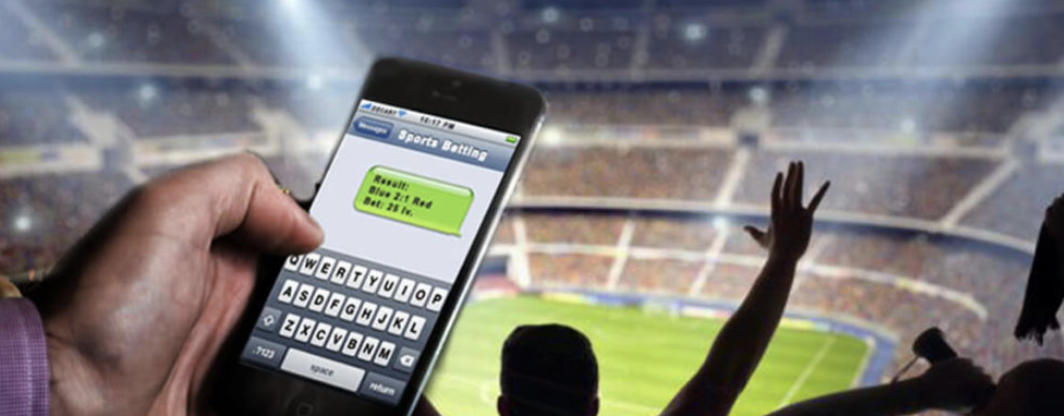 Individual on a mobile phone placing a bet at a stadium game
